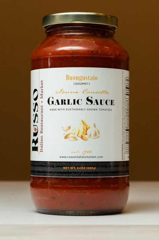 Jar of garlic sauce with a visible label on a wooden surface.