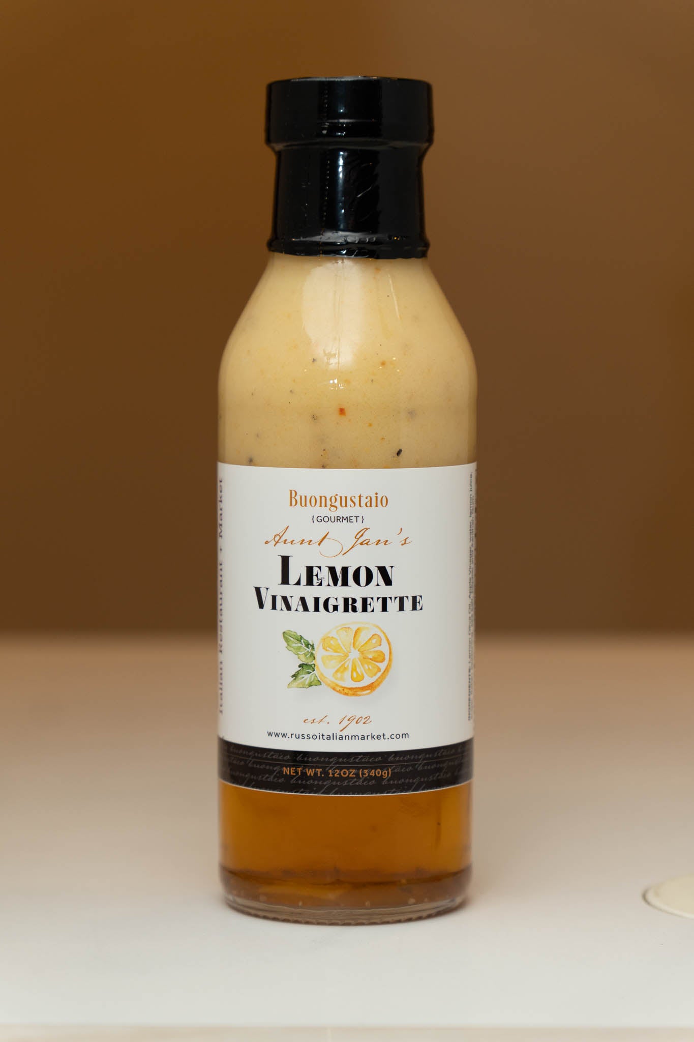 Bottle of lemon vinaigrette dressing with a label on a neutral background