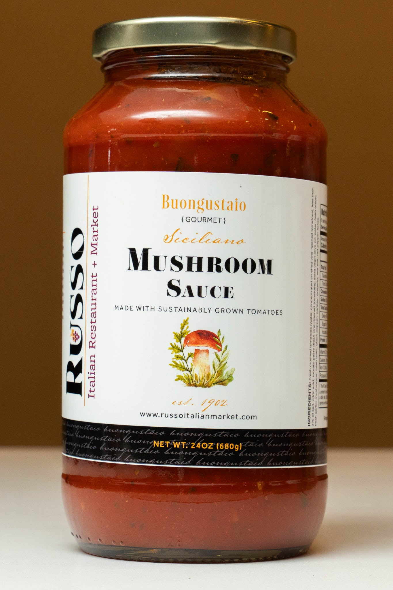 Jar of mushroom sauce with a label on a plain background