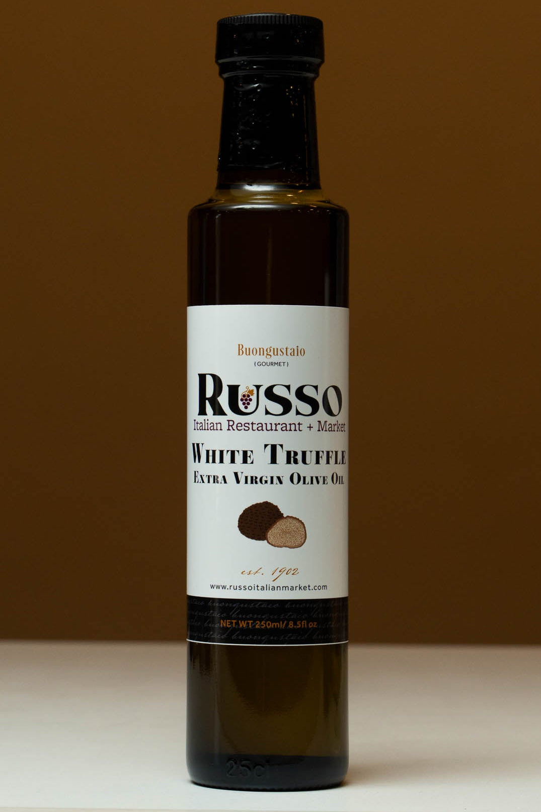 Bottle of Russo White Truffle Extra Virgin Olive Oil on a white surface with a brown background
